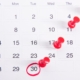 a calendar with red push buttons pinned to it